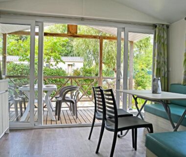 Salon ouvert sur terrasse en bois avec table et chaises au Camping Les Castors