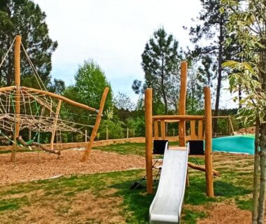 Aire de jeux en bois près de la piscine au Camping Les Charmes