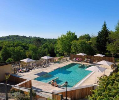 Piscine extérieure entourée de transats et parasols au Camping Les Charmes