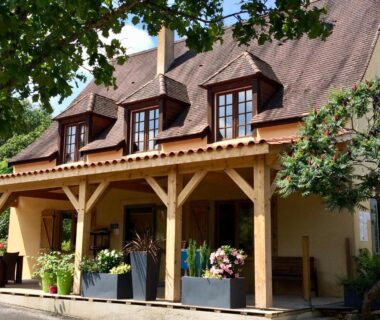 Terrasse en bois avec jardinières devant la façade du Camping Les Charmes