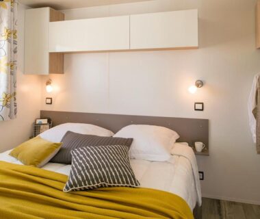 Chambre de mobil-home avec lit double et luminaires dans le Camping Les Chênes Verts