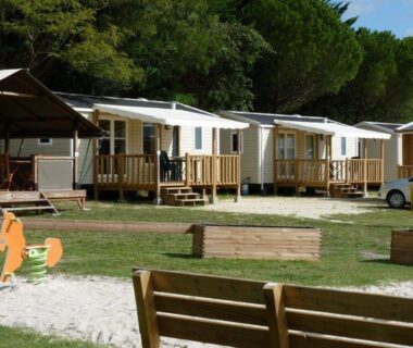 Allée bancs et mobil-homes au milieu des pins dans le camping Les Chênes Verts