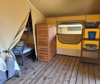 Intérieur de tente avec lits superposés et rangement au Camping Les Chênes Verts