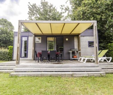 Terrasse couverte avec table à manger et transats au Camping Les Chèvrefeuilles