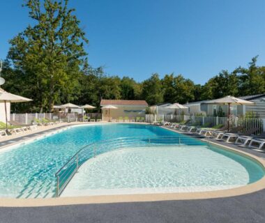 Piscine extérieure avec transats et parasols au Camping Les Chèvrefeuilles
