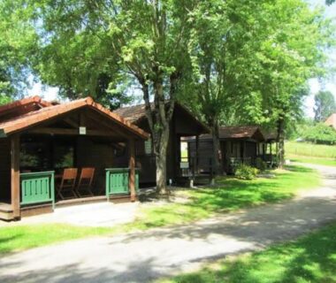 Allée ombragée bordée de chalets en bois au Camping Les Etoiles