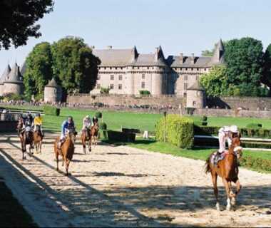Allée bordée de jardins avec cavaliers devant un château au Camping Les Etoiles