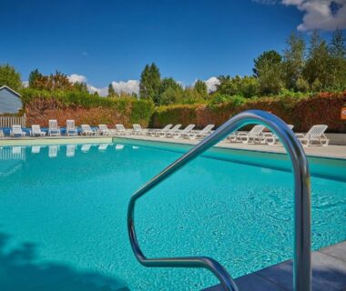 Piscine extérieure avec échelle et transats au Camping Les Fontaines