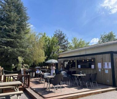 Terrasse extérieure avec tables chaises et parasols au Camping Les Fontaines