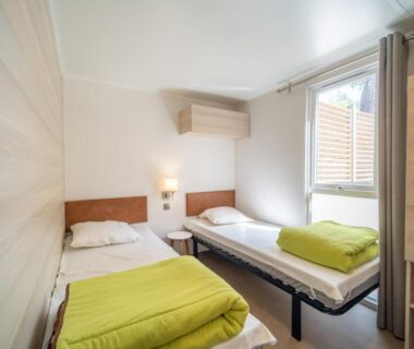 Intérieur de la chambre avec deux lits simples et climatisation au Camping Les Genêts