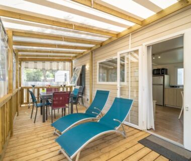 Terrasse couverte avec transats et coin repas au Camping Les Genêts