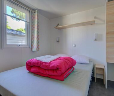 Chambre avec lit double et fenêtre au Camping Les Jardins d Agathe