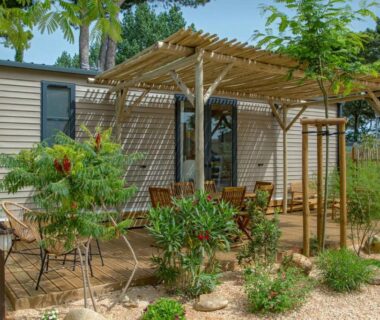 Terrasse ombragée avec pergola et mobilier de jardin devant mobil-home au Camping Les Jardins d Agathe
