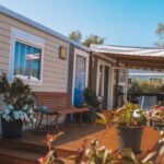 Terrasse en bois avec pots de fleurs et banc du mobil-home Camping Les Jardins de la Mer