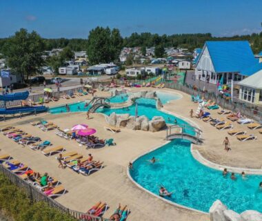 Piscine extérieure avec toboggans et transats au Camping Les Jardins de la Mer