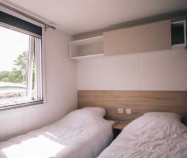 Chambre avec deux lits simples et fenêtre dans l'hébergement du Camping Les Jardins de la Mer
