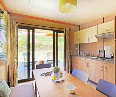 Séjour avec kitchenette et terrasse baignée de lumière au Camping Les Lavandes