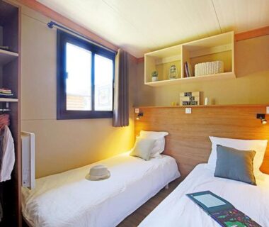 Chambre avec deux lits simples et rangement dans le mobil-home du Camping Les Lavandes