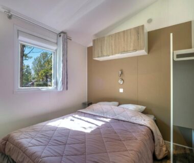 Chambre double lumineuse avec lit et fenêtre au Camping Les Mizottes