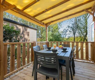 Terrasse couverte avec table et chaises dans le locatif au Camping Les Mizottes