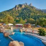 Piscine extérieure avec rochers et transats au Camping Les Oliviers