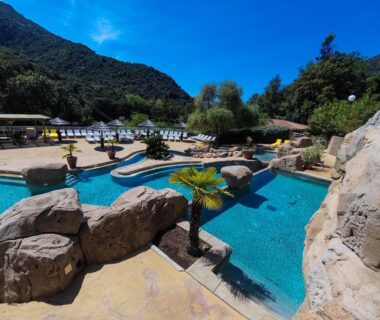 Piscine extérieure avec bassins rochers et transats au Camping Les Oliviers