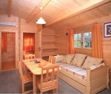 Intérieur de chalet avec coin repas et banquette au camping Les Oliviers