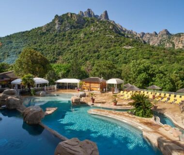 Complexe de piscine avec transats parasols et rochers au Camping Les Oliviers