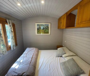 Chambre double avec lit et fenêtres dans un hébergement au Camping Les Oliviers