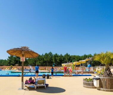 Solarium avec transats et parasols au bord de la piscine du Camping Les Oyats