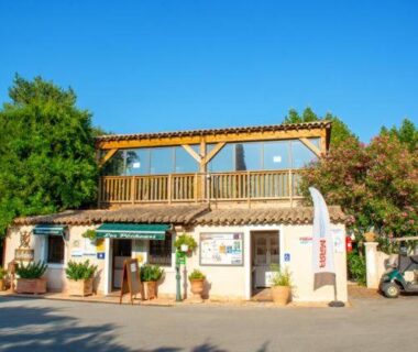 Façade du bâtiment d'accueil avec terrasse et végétation au Camping Les Pêcheurs Maeva