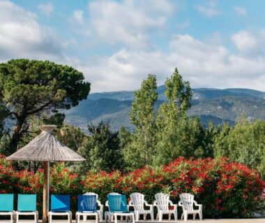 Bord de piscine avec transats et parasol au Camping Les Pins Bord de mer