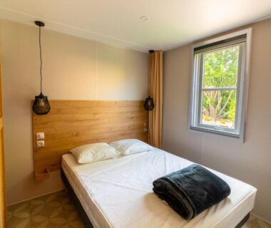 Chambre avec lit et fenêtre au Camping Les Pins Bord de mer