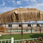 Piscine couverte et parasol en paille au Camping Les P'tites Maisons dans la Prairie