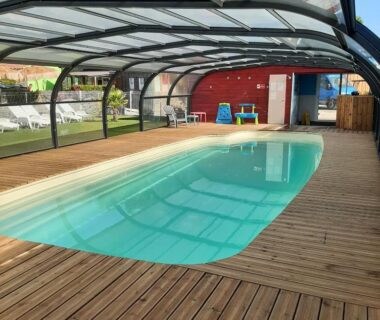 Piscine couverte avec terrasse en bois au Camping Les P'tites Maisons dans la Prairie