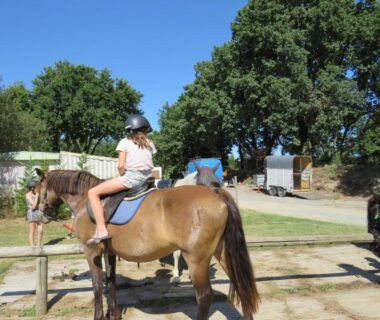 Aire de poneys avec enfant à cheval au Camping Les P'tites Maisons dans la Prairie