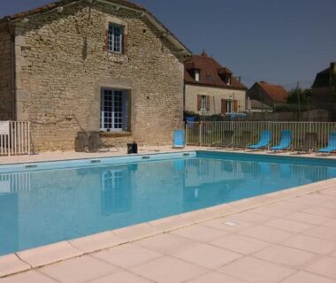 Piscine extérieure devant maisons en pierre au Camping Les Rives du Céou