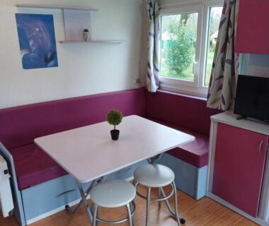 Intérieur coin repas avec banquette et table dans le mobil-home du Camping Les Rives du Céou