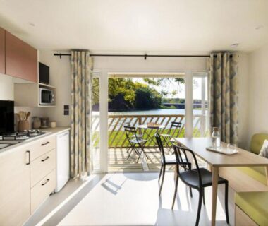 Séjour avec kitchenette et terrasse donnant sur l'étang au Camping Les Sables Blancs