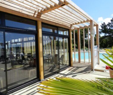 Terrasse sous pergola et piscine extérieure au Camping Les Sables Blancs