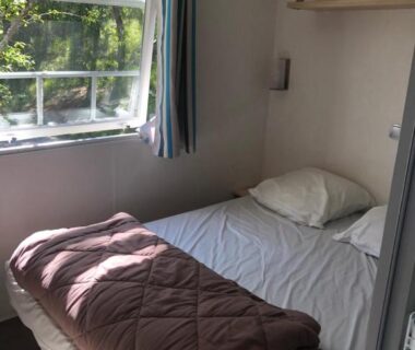 Chambre avec lit et fenêtre au Camping Les Terrasses de Dordogne