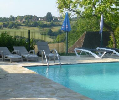 Bord de piscine avec transats et parasols dans la campagne au Camping Les Terrasses de Dordogne