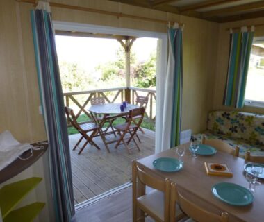 Terrasse en bois avec table et chaises vue depuis le séjour au Camping Les Terrasses de Dordogne