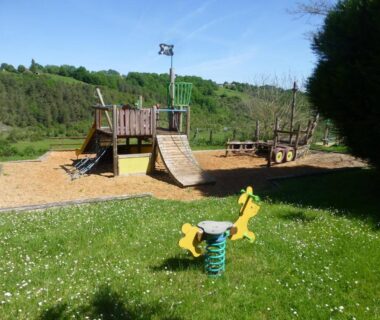 Aire de jeux avec structure en bois et bascule au Camping Les Terrasses de Dordogne