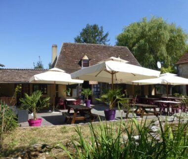 Terrasse extérieure avec parasols et tables au Camping Les Terrasses de Dordogne