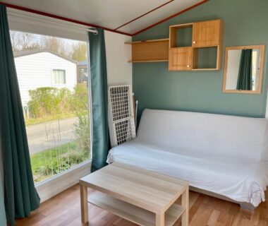 Intérieur de mobil-home avec canapé et table basse au Camping Les Tourterelles
