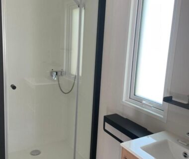 Salle de bain avec cabine de douche et lavabo au Camping Les Tourterelles
