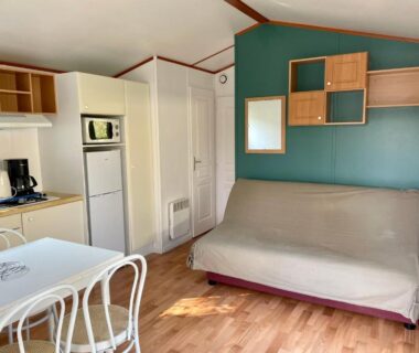 Intérieur de mobil-home avec canapé et kitchenette au Camping Les Tourterelles
