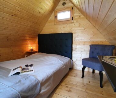 Chambre mansardée en bois avec lit et chaise dans le Camping Les Vernieres La Bourboule Sancy