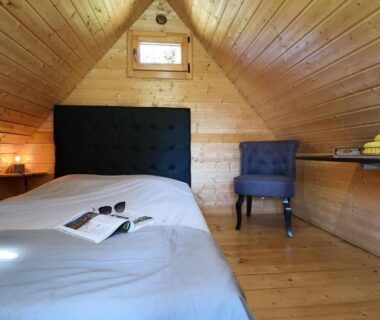 Mansarde en bois avec lit simple et chaise dans le Camping Les Vernieres La Bourboule Sancy